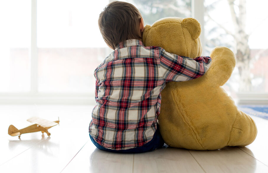 child cuddling teddy