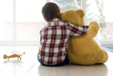 child cuddling teddy