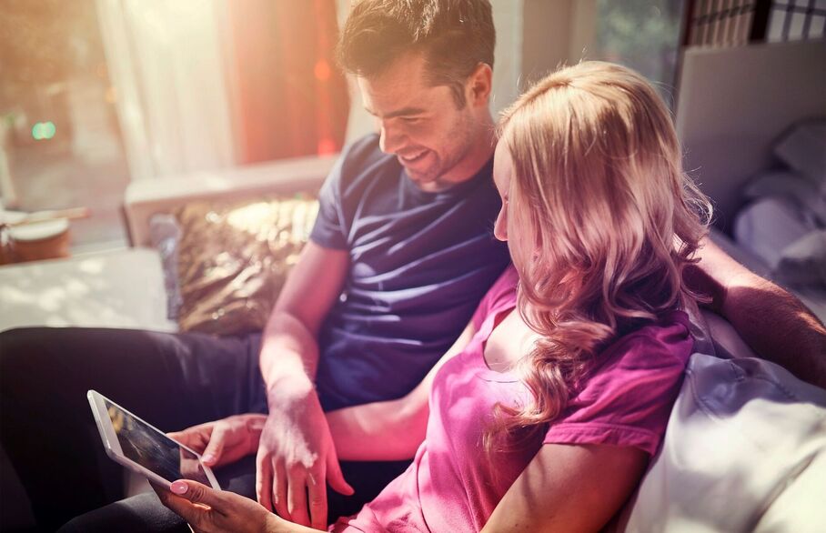 couple sat on sofa on tablet