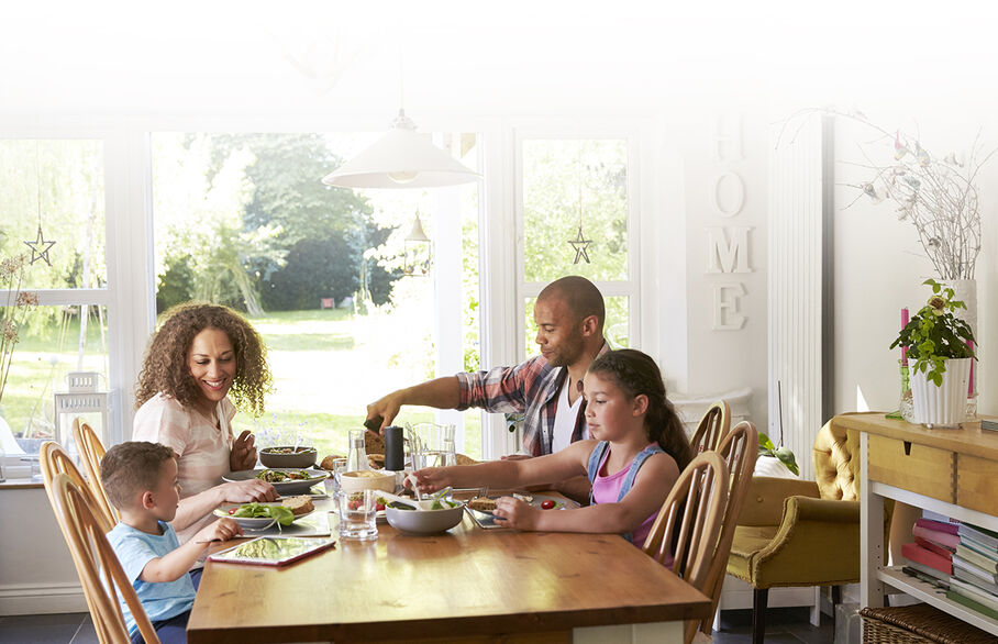 Happy family of 4 having dinner at dining table