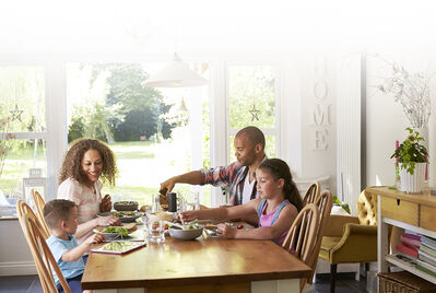 Happy family of 4 having dinner at dining table