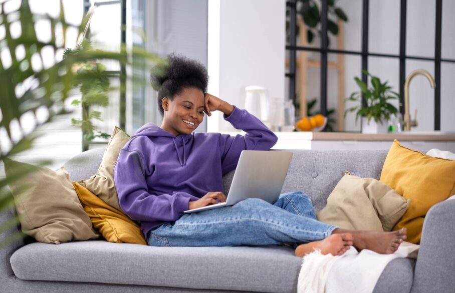 woman laid on sofa with laptop in lap