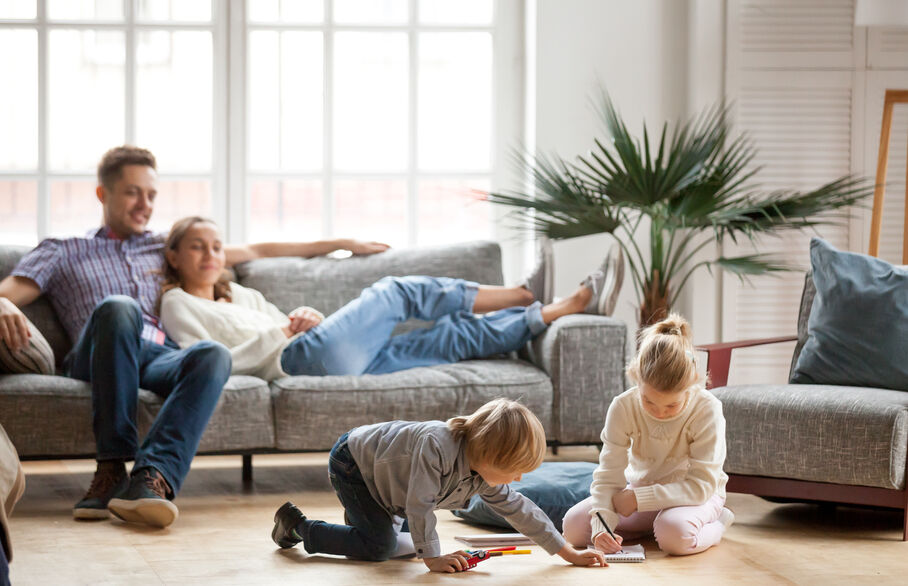 Couple sitting on sofa with kids playing on floor