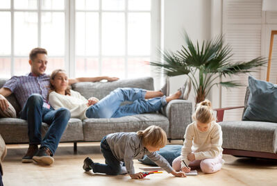 Couple sitting on sofa with kids playing on floor